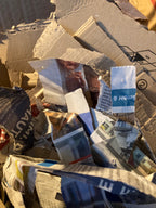 Pile of crumpled newspaper and paper bags with visible text and logos.