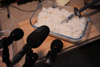 Container of white rice with microphones on a wooden surface